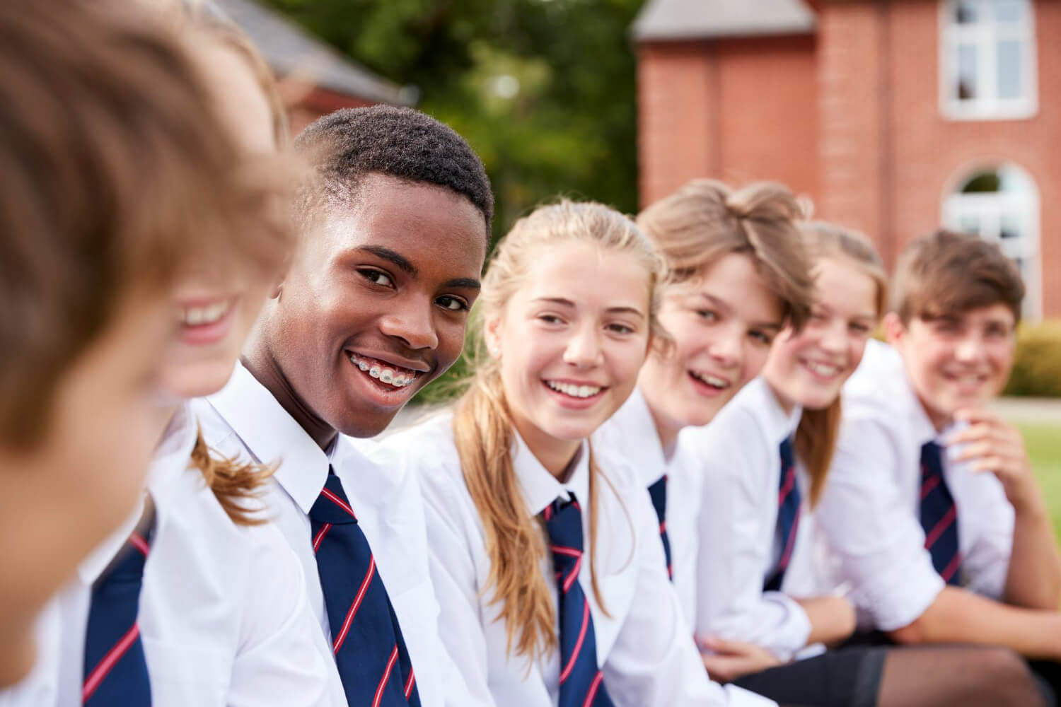 Group of teenage students in uniform outside school buildings